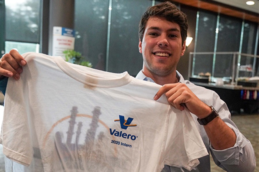 Young Man holding up a t-shirt that says "Kooilspetroleum 2020 Intern"